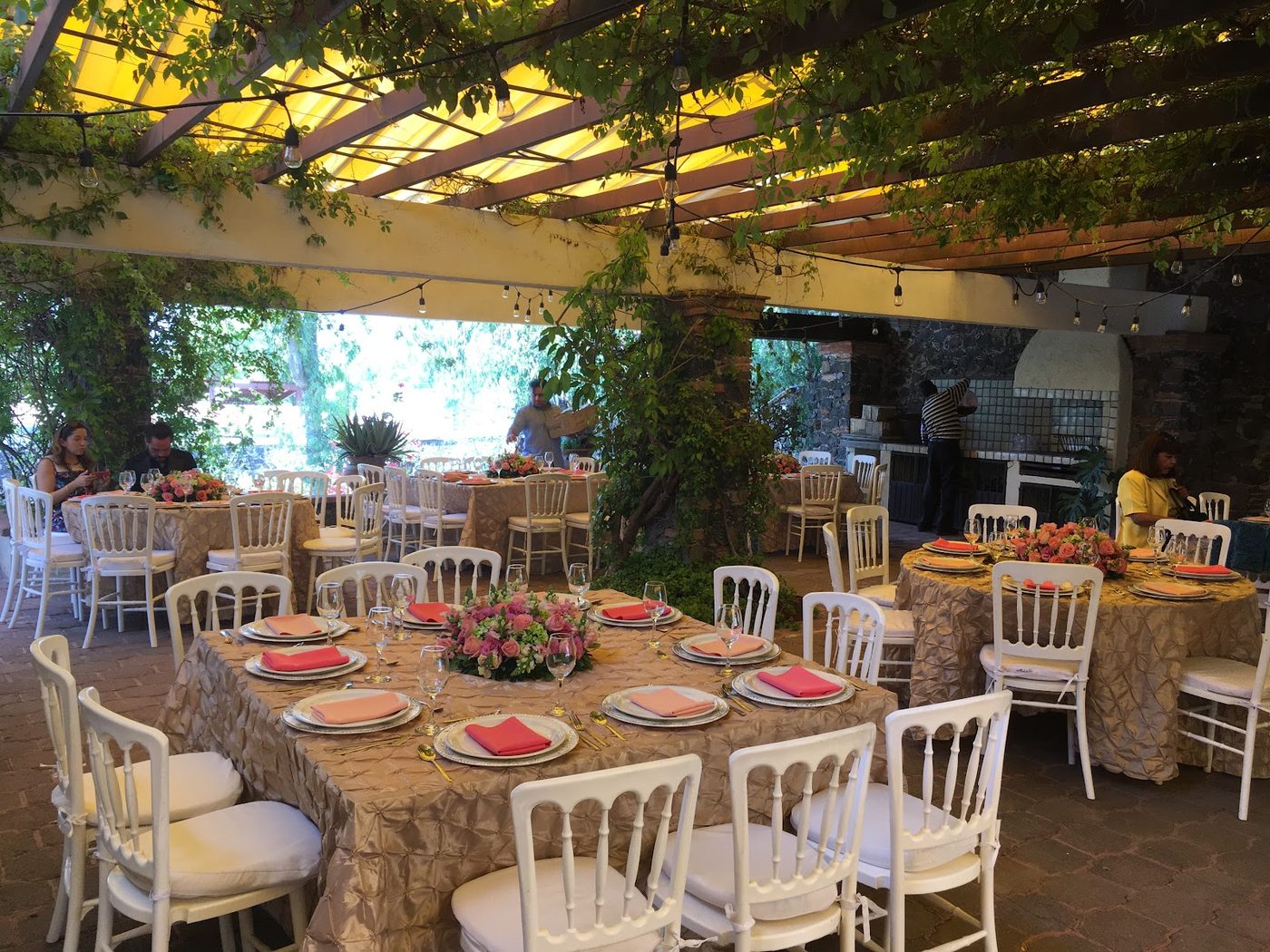 Evento montado en tonos coral bajo la pérgola de la quinta