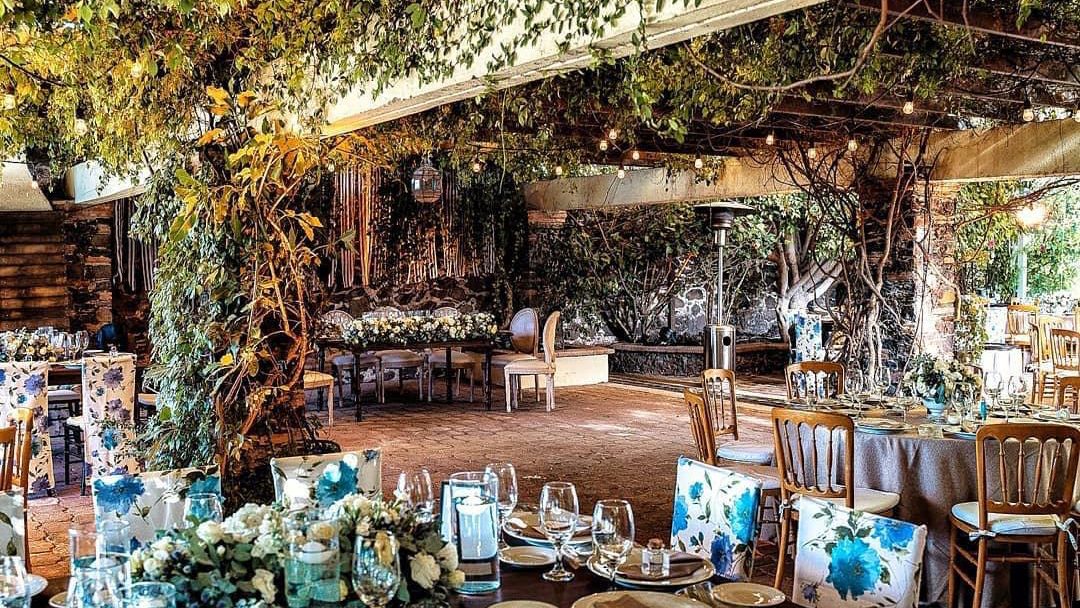 Jardín de Quinta Cabuya con pérgola cubierta de enredadera y mesas montadas para una boda